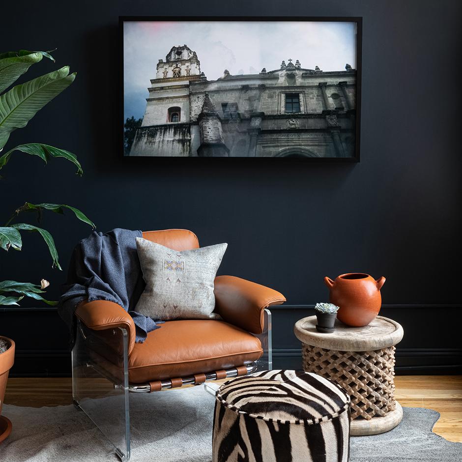 Iris Cactus Silk throw pillow on tan leather chair in dark living room with plant, wooden side table and zebra ottoman