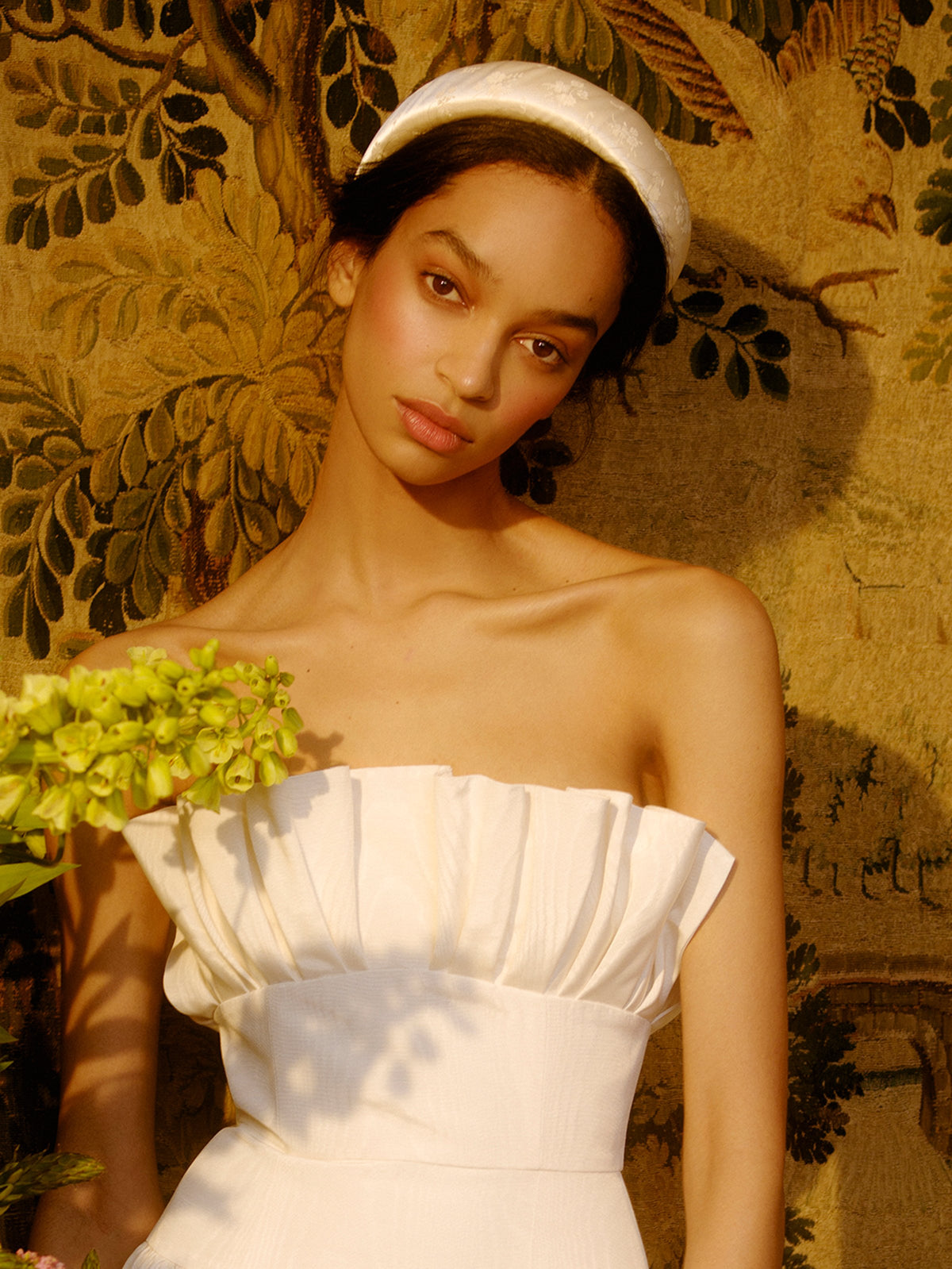 Markarian x Gigi Burris Bruna Sculptural Padded Headband on a model, showing white satin padding against patterned upholstery