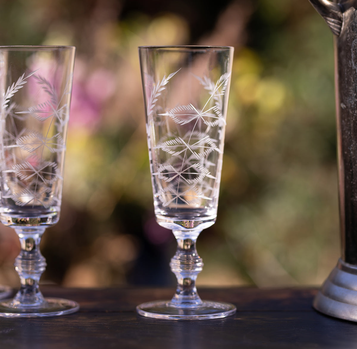 Front view of Crystal Champagne Flutes with Fern Design, Set of Four showcasing hand-engraved fern patterns with blurred greenery