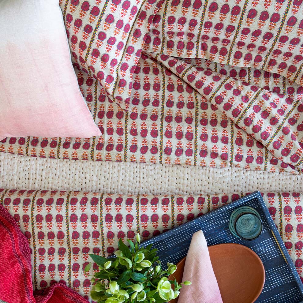 Overhead view of Fuchsia Daisy Suzani Duvet Cover showcasing its red and pink floral pattern on a styled bed