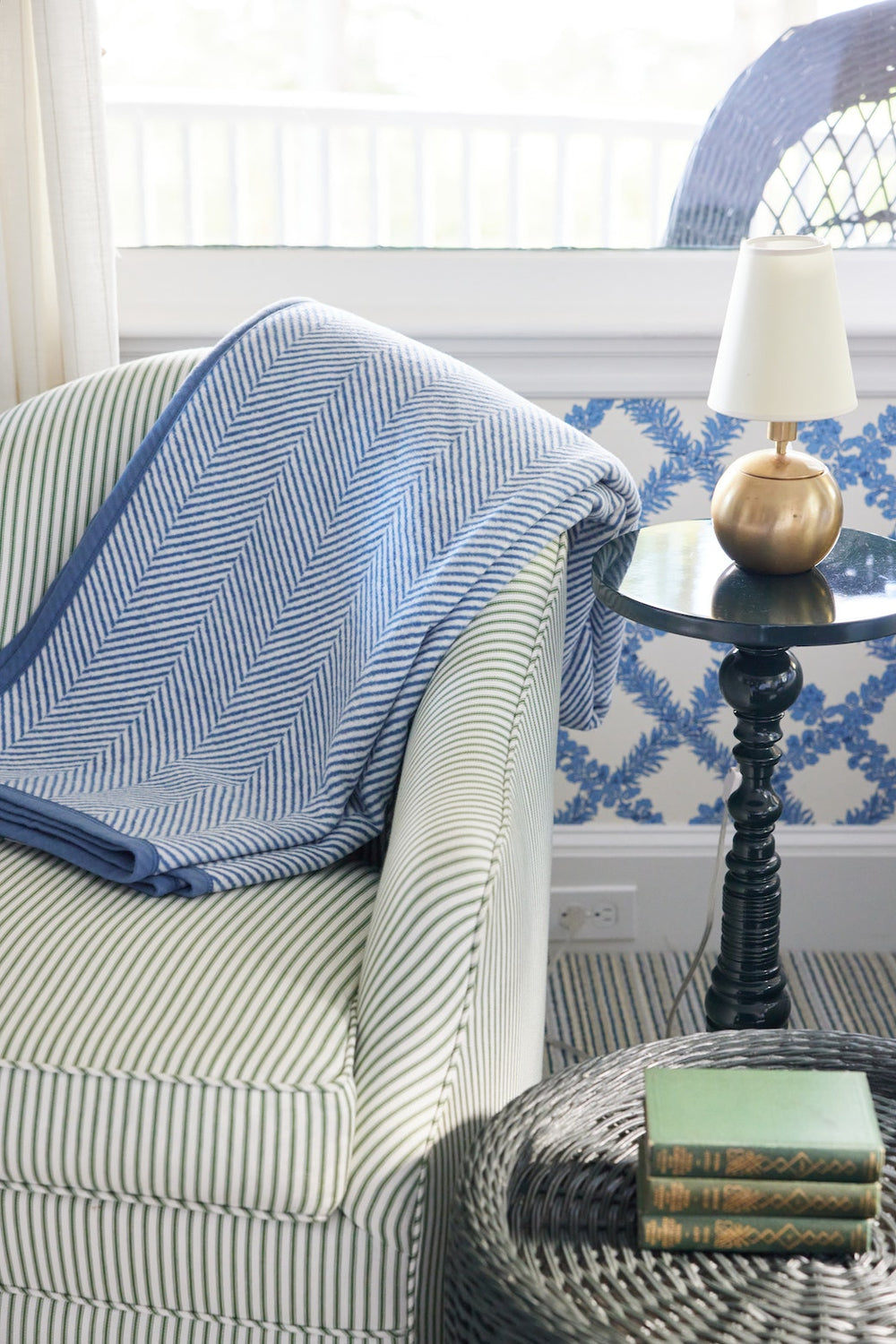 Harborview Herringbone light blue blanket draped over a striped armchair, showing herringbone pattern and blue edging