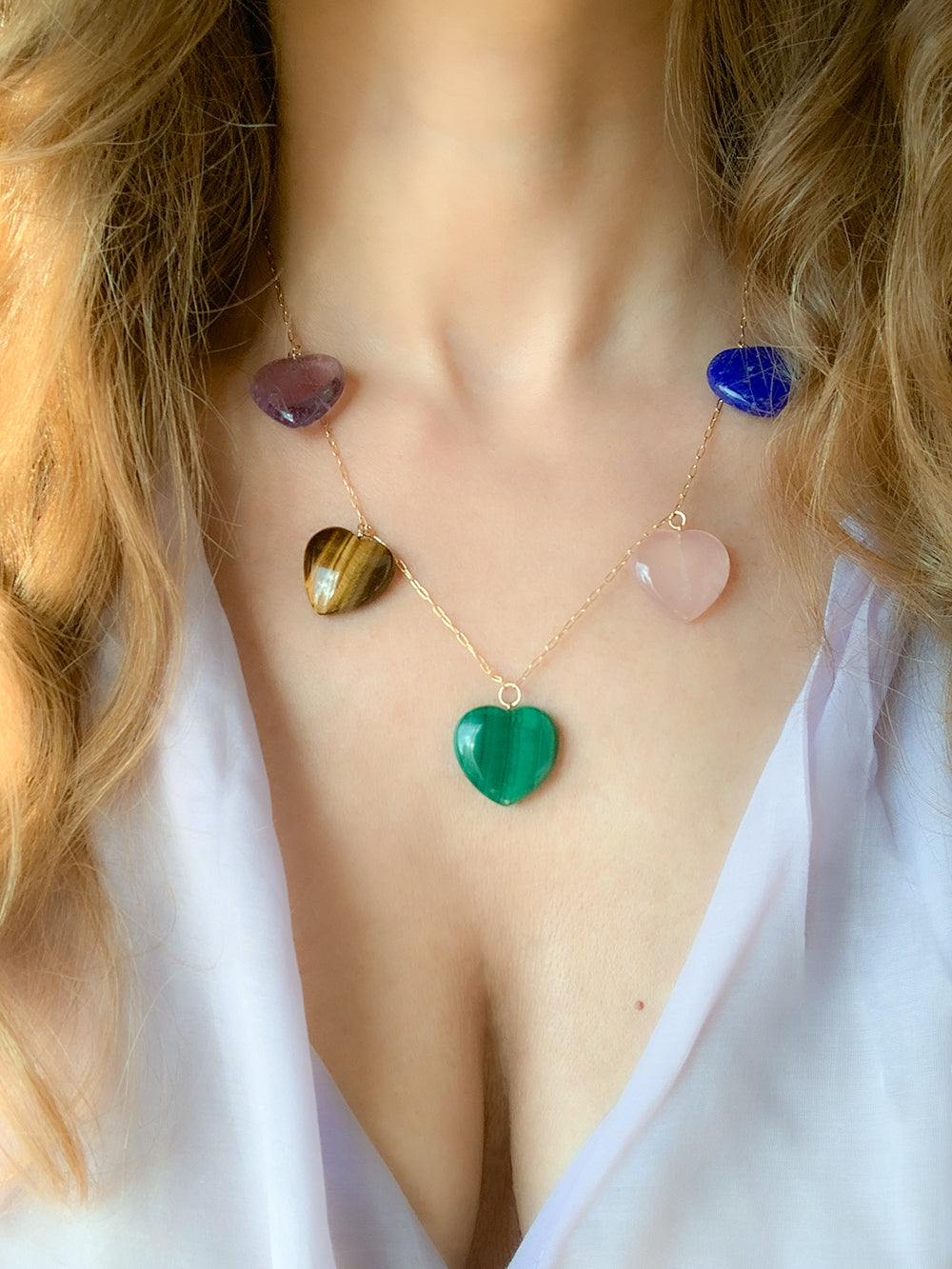 Close-up of Multi Gem Heart Necklace showing five hand-carved gemstone hearts on an 18K yellow gold chain worn by a model