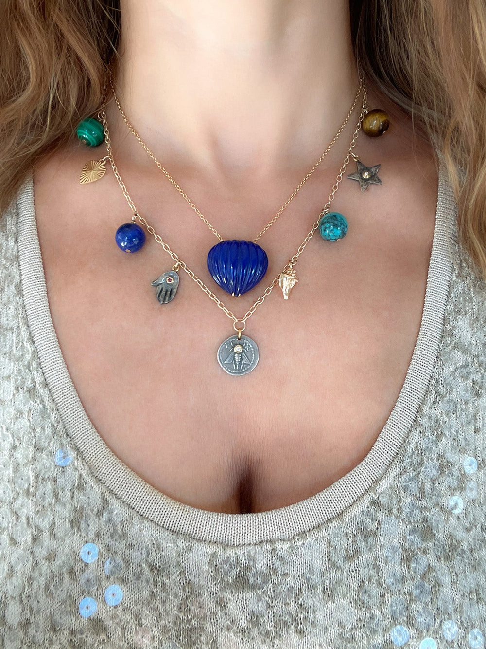 Close-up of Les Charmantes necklace on model showcasing nine mixed-metal charms and a blue shell pendant