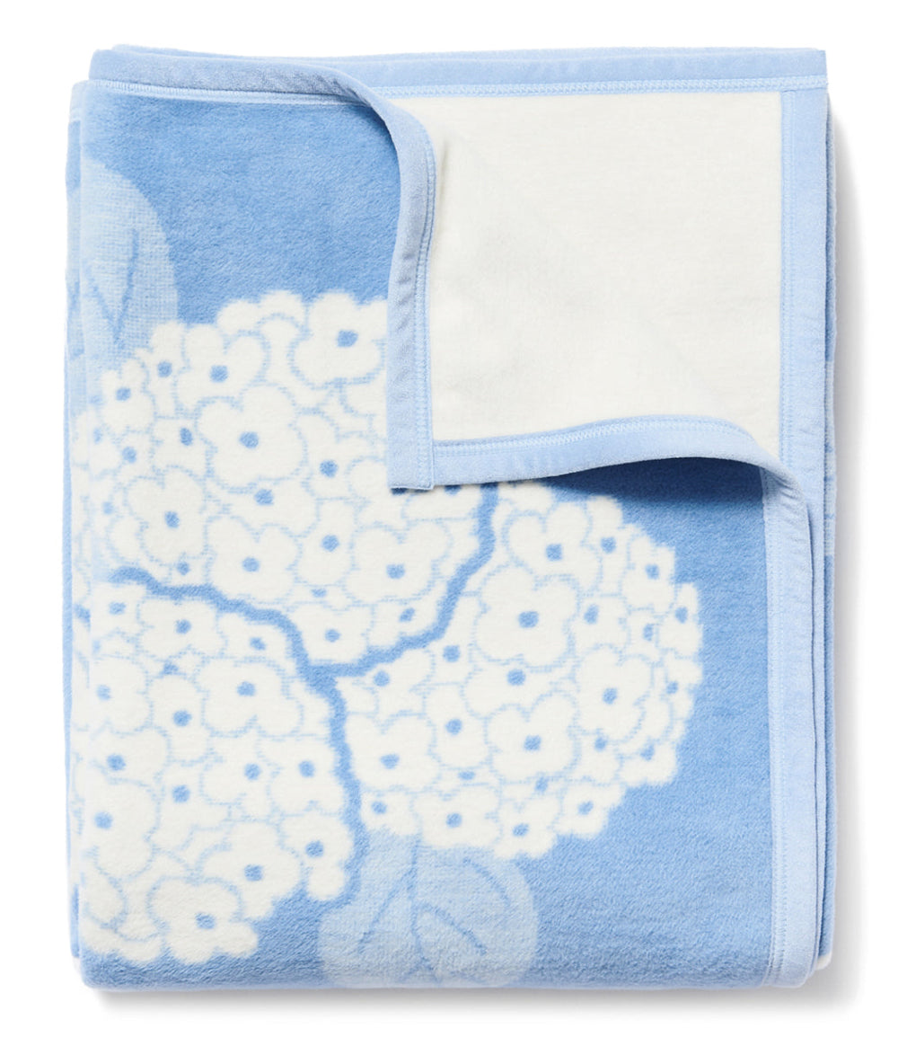 Folded Hydrangeas Bluebell blanket showing blue hydrangea jacquard floral pattern and white reverse on white background