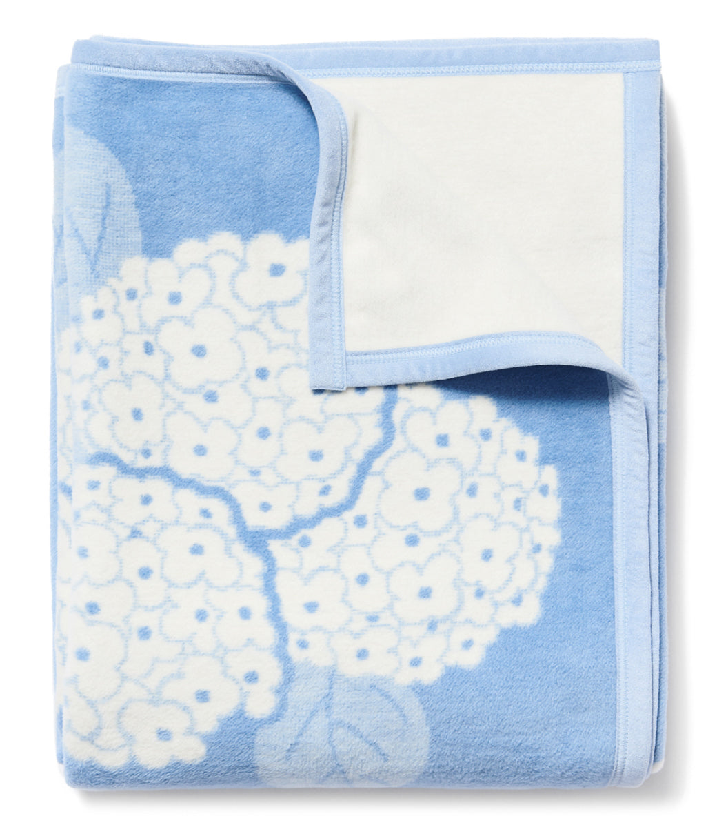 Folded Hydrangeas Bluebell blanket showing blue hydrangea jacquard floral pattern and white reverse on white background