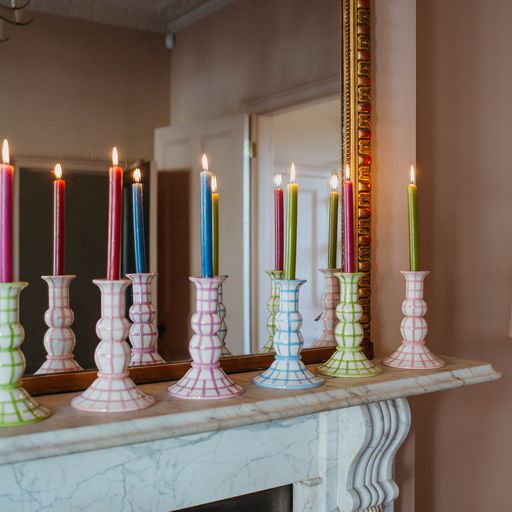 Front view of Lumiere Gingham candle holder showing pastel gingham pattern holding a lit taper candle on a marble mantel