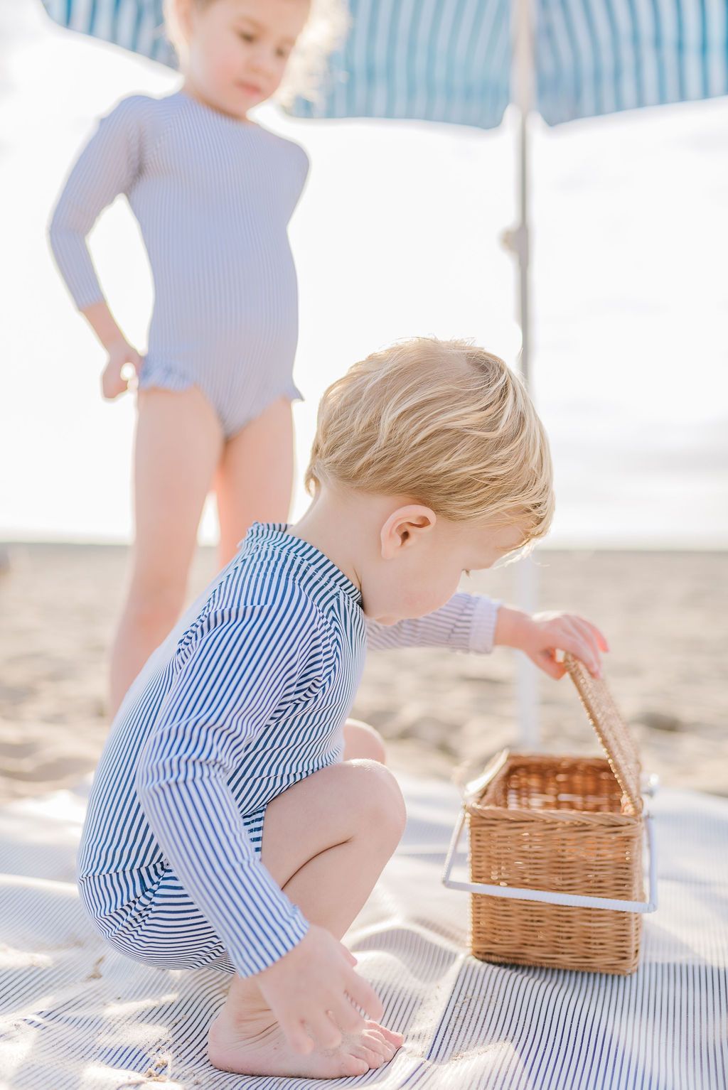 Side view of blue and white striped Boys Rashguard One-Piece showcasing long sleeves and a close fit on a child by a pool