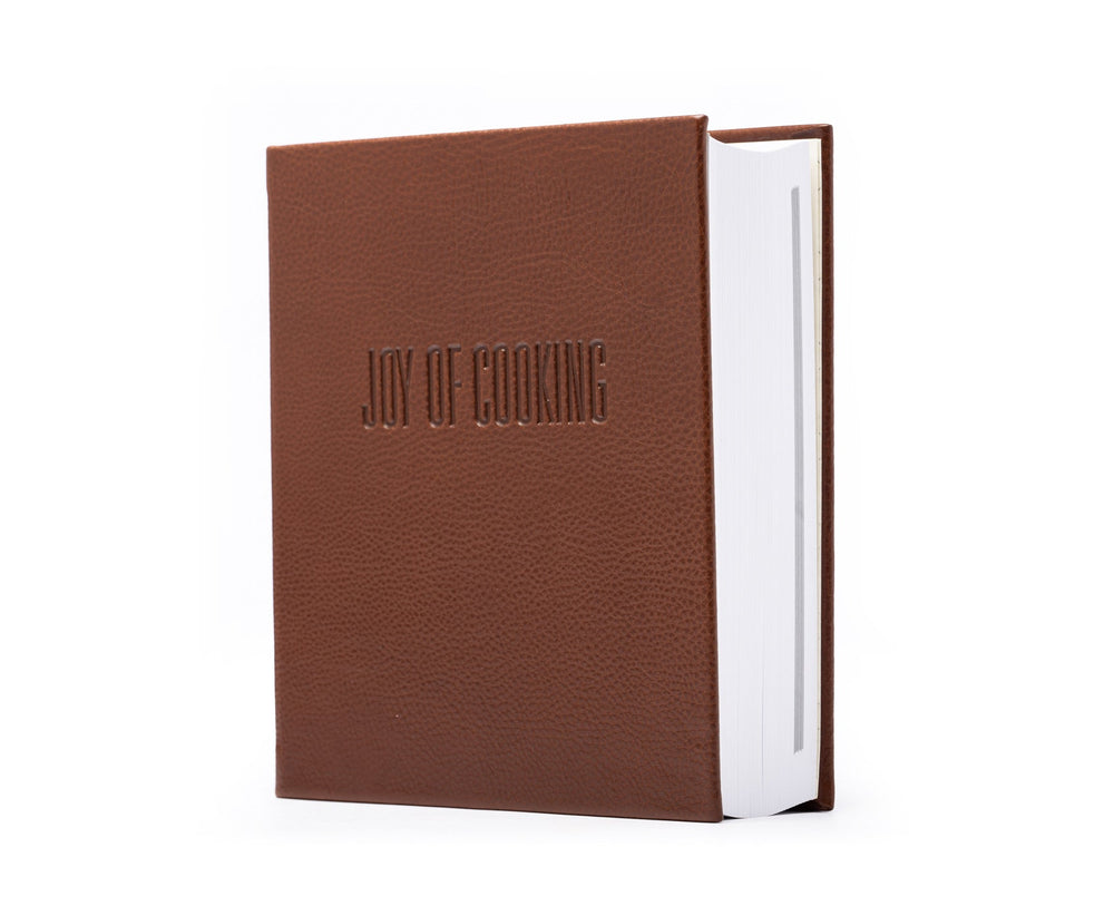 Front three-quarter view of Joy of Cooking book in vintage chestnut leather with embossed JOY OF COOKING on white background