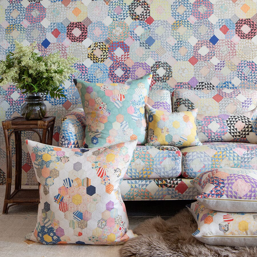 Butter Diamond Quilt pillows arranged on a matching quilted sofa with a side table, vase of white flowers, and a faux fur rug
