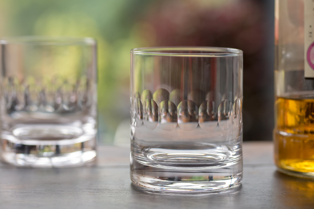 Close-up view of Pair of Crystal Whiskey Glasses with Lens Design showing hand-engraved pattern on a bar