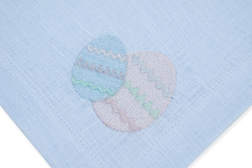 Close-up of Easter Egg Blue linen napkin showcasing embroidered pastel egg motif on light-blue linen background