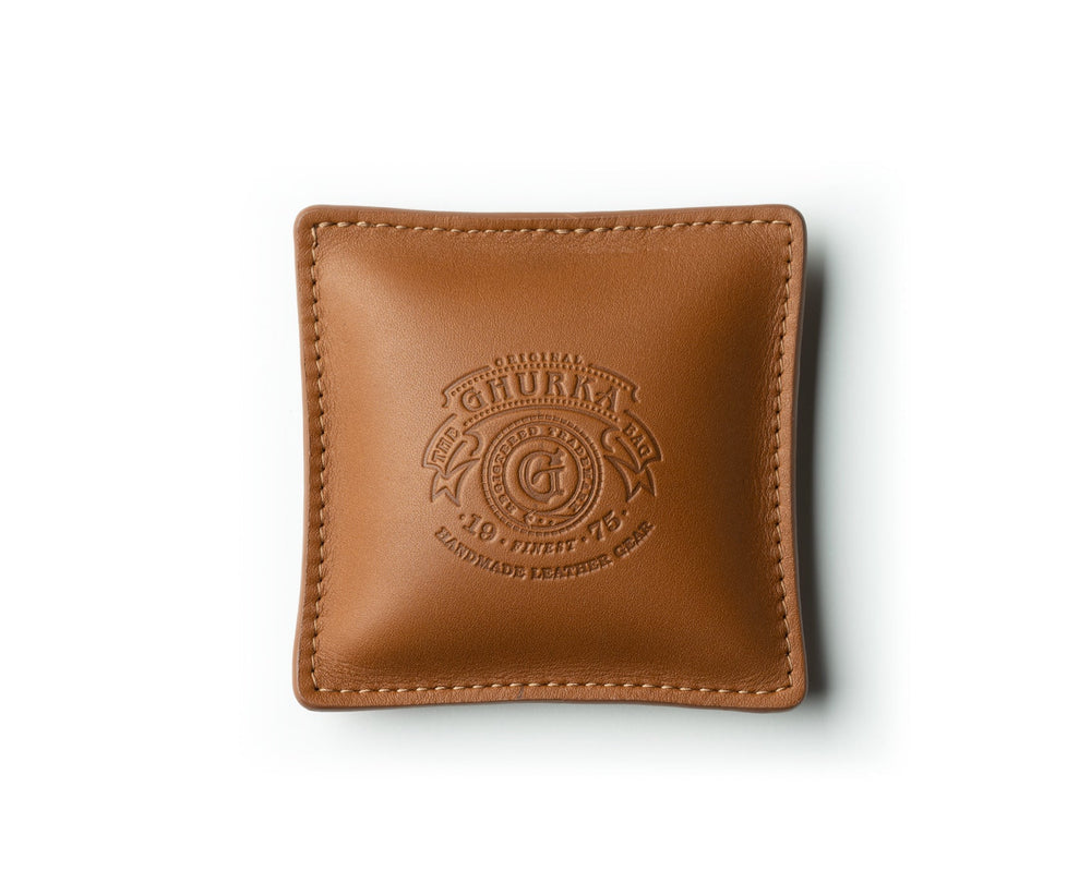 Top view of chestnut leather paperweight showcasing embossed Ghurka logo and stitched edges on white background