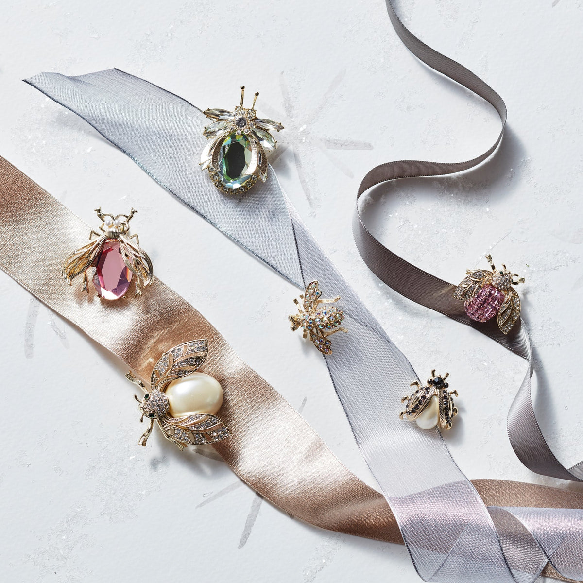 Close-up of Classic Sparkle Clip Set in Pastel showcasing jeweled insect clips with pastel ribbons on a white background