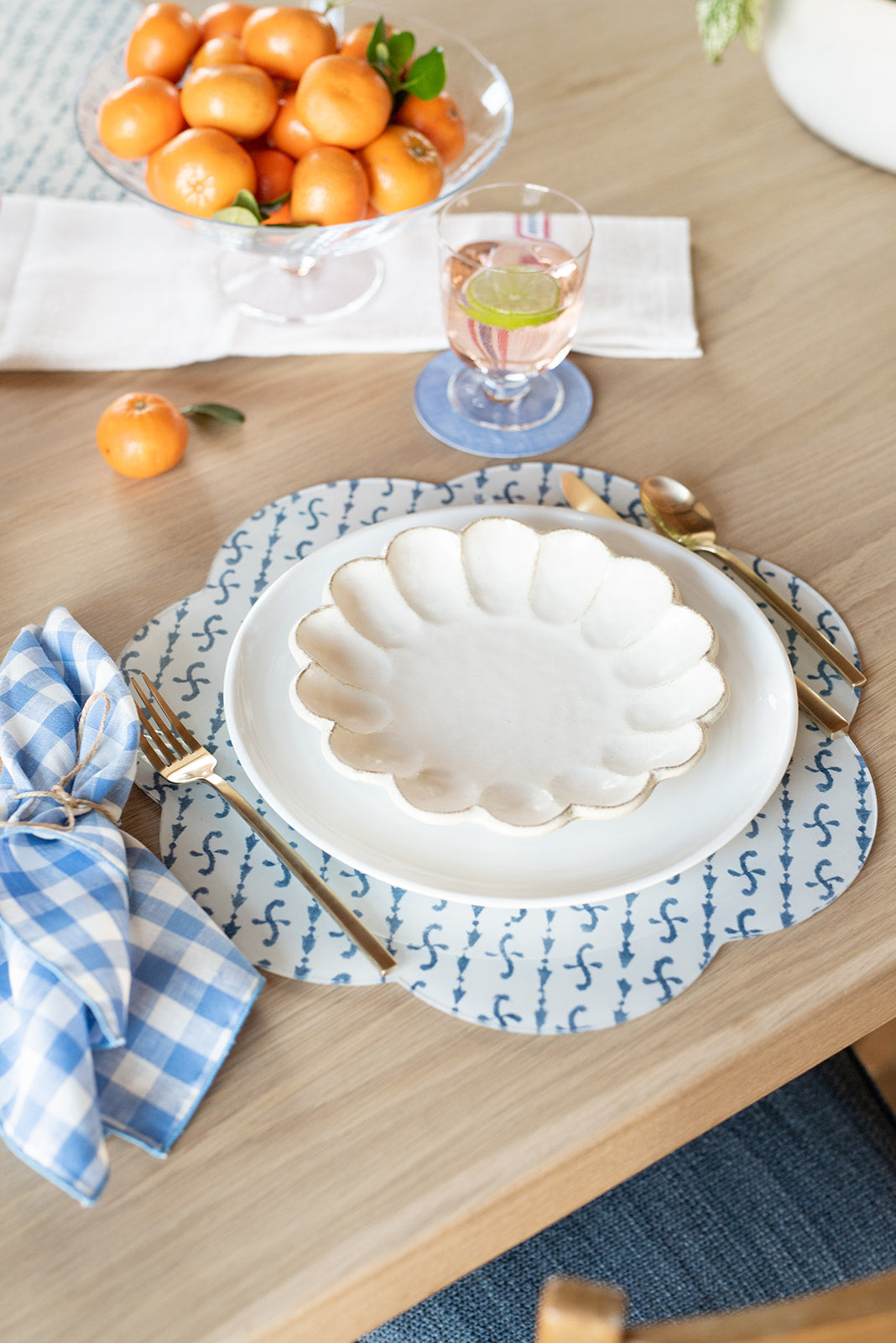 Three-quarter view of Brooks Block Print placemat showing blue-and-white block-print diagonal stripe and scalloped edge on a wooden table