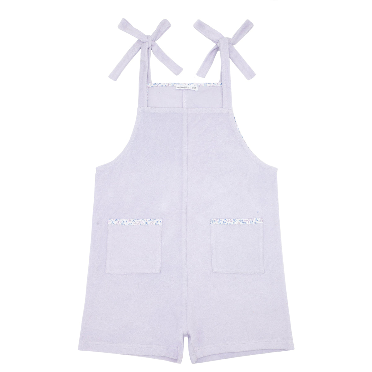 Front view of Girls Bay Lavender French Terry Romper showcasing adjustable tie straps and front pockets on a white background