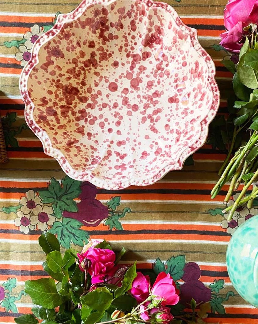 Top view of Speckled Serving Bowl in Burgundy showing scalloped edges and speckled pattern on a floral striped background