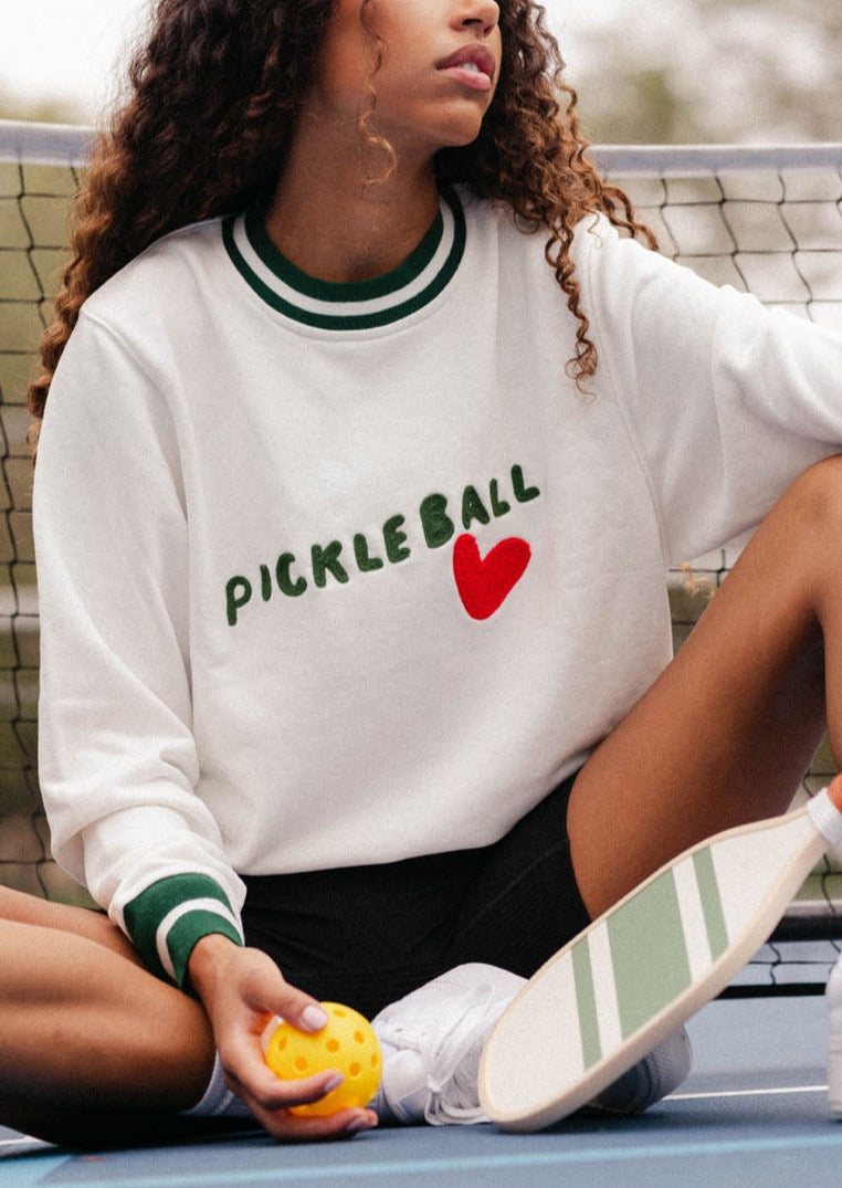 Front view of cream Pickleball Heart sweatshirt on model, green-striped trim, PICKLEBALL text and red heart on chest