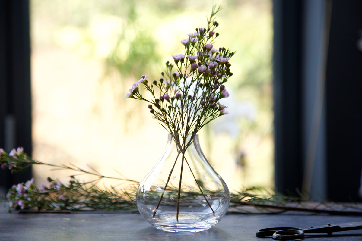 Front view of Small Crystal Vase with Stars Design showcasing hand-engraved stars with flowers on a windowsill